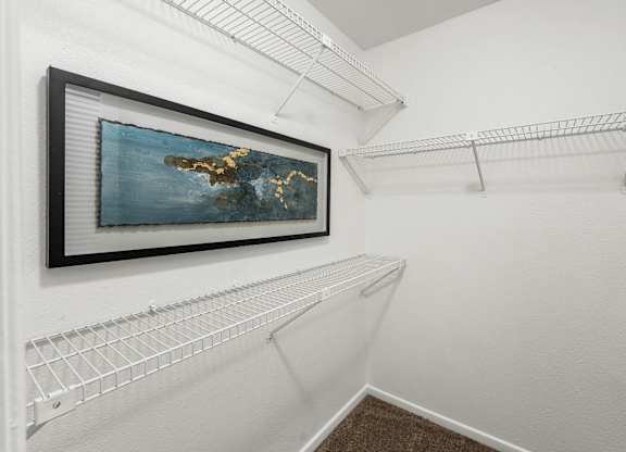 A picture of an island is hanging on a wall above a shelf.