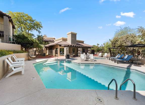 A swimming pool surrounded by lounge chairs and umbrellas.