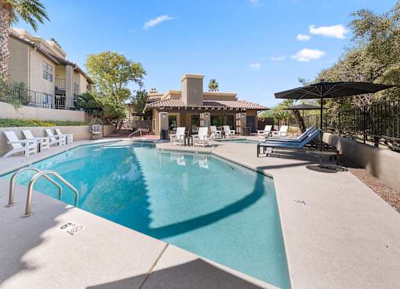 A swimming pool in a backyard with a patio and a pool house.