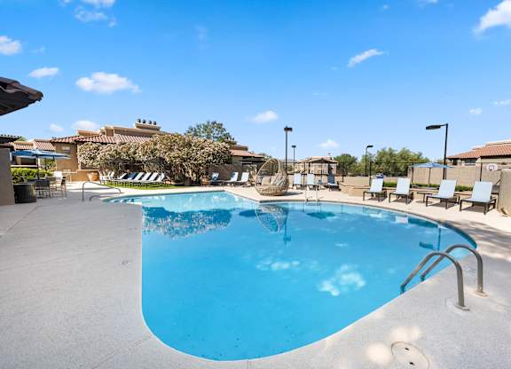 A large outdoor swimming pool with a sun lounger and poolside table.