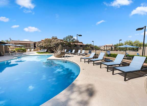 A pool with sun loungers and a blue sky.