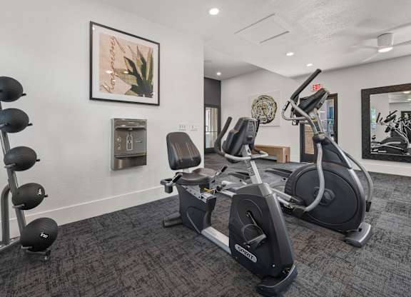 A gym room with a row of exercise bikes and a mirror.