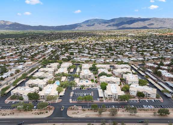 A large suburban area with a parking lot in the foreground and mountains in the background.
