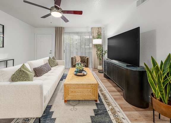 A living room with a white couch, a wooden coffee table, and a flat screen TV.