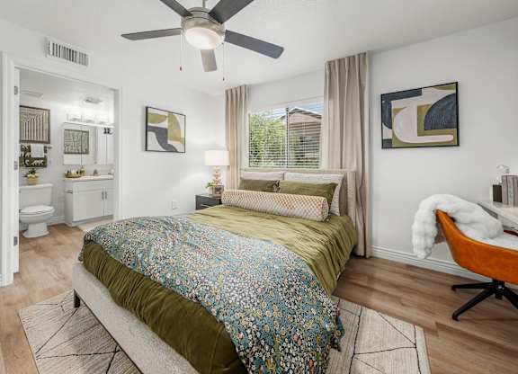 A bedroom with a bed, a chair, and a ceiling fan.