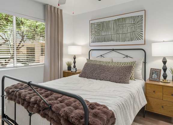 A bedroom with a bed, nightstand, and a painting on the wall.