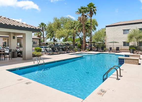 A swimming pool surrounded by palm trees and a building in the background.