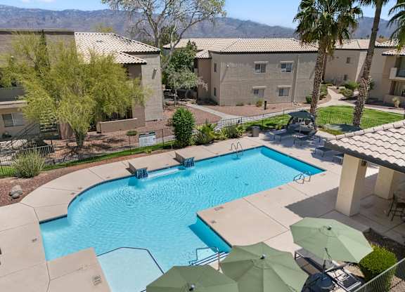 A swimming pool surrounded by palm trees and umbrellas.