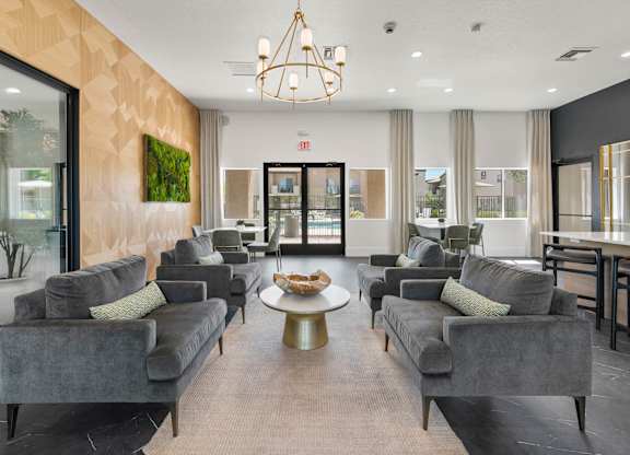 A living room with grey couches and a chandelier.