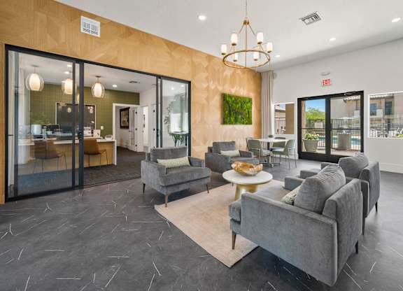 A living room with a grey couch and a chandelier.