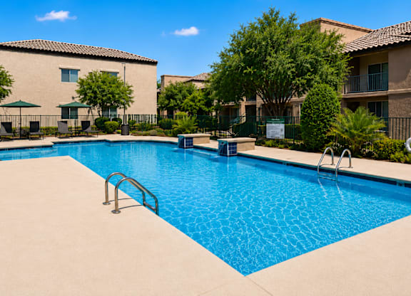 A swimming pool surrounded by a fence and trees.