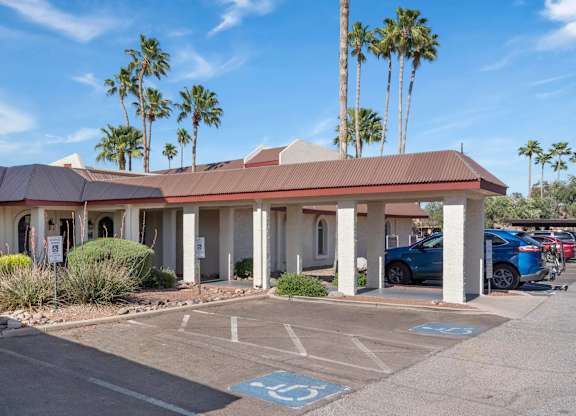 A parking lot with a building and palm trees in the background.