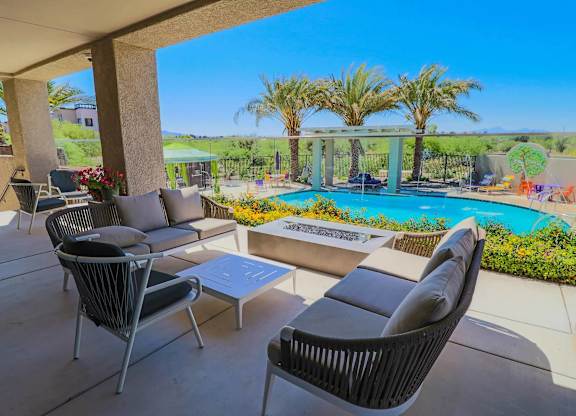 A patio with a pool and chairs.
