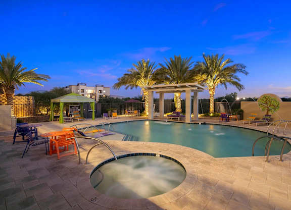 A pool surrounded by palm trees and a gazebo.