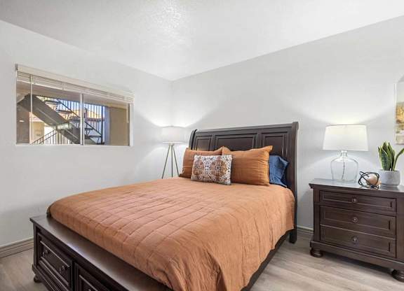 A bedroom with a bed, nightstand, and a window.