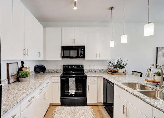 A black refrigerator is in a kitchen with white cabinets.