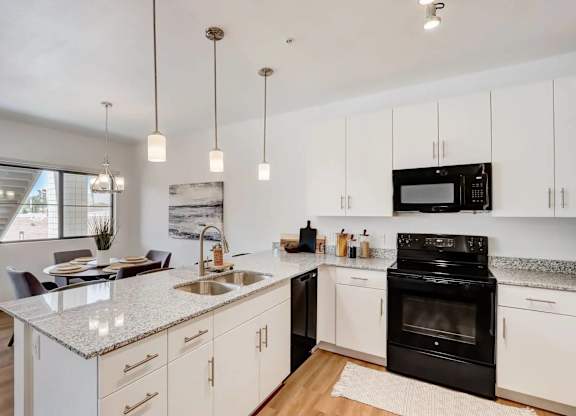 A modern kitchen with a black oven and white cabinets.