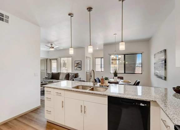 A modern kitchen with a black dishwasher and white cabinets.