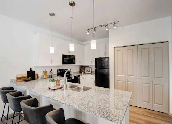 A kitchen with a granite countertop and a black refrigerator.
