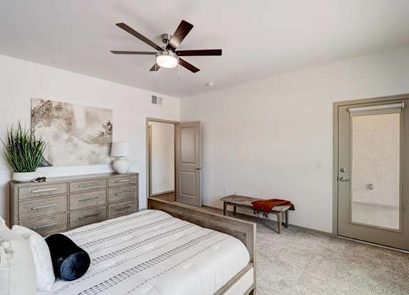 A bedroom with a bed, dresser, and a ceiling fan.