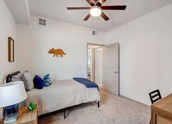 A bedroom with a bed, a ceiling fan, and a wooden table.