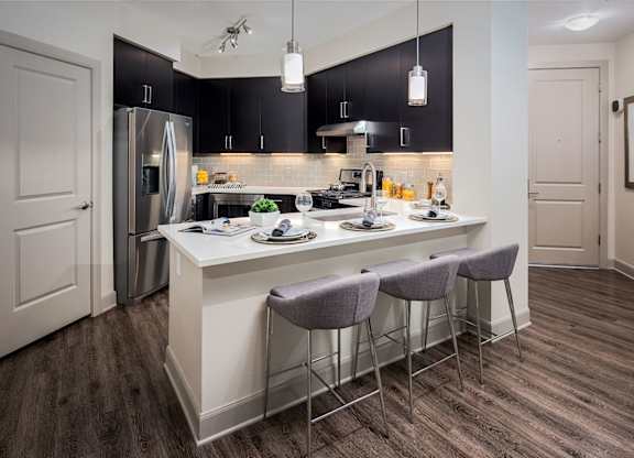 A kitchen with a white island and grey bar stools.