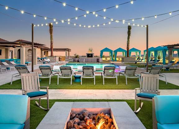 A patio with a fire pit and chairs.