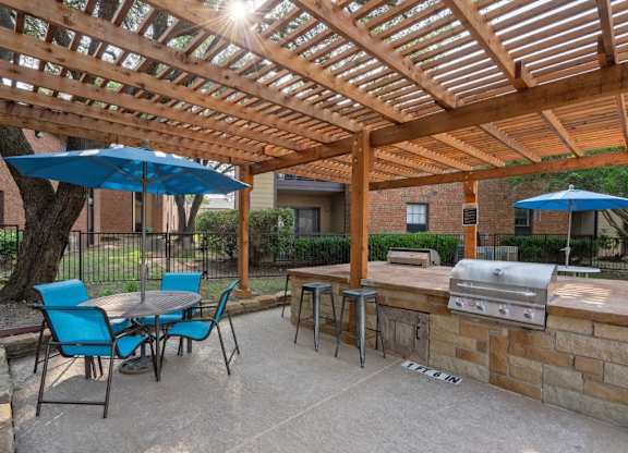 A patio with a table and chairs under a wooden pergola.
