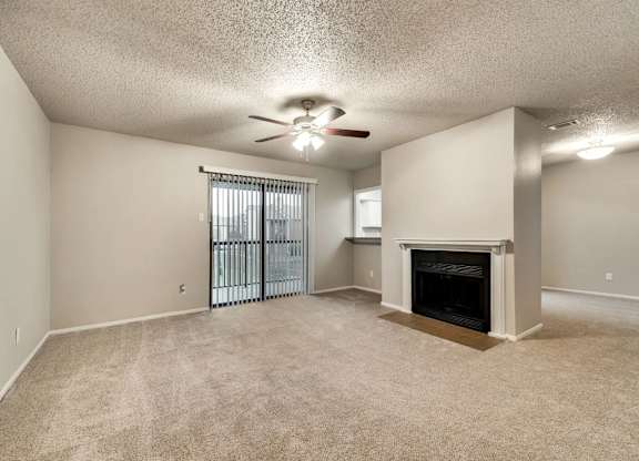 A sparsely furnished living room with a fireplace and sliding glass doors.