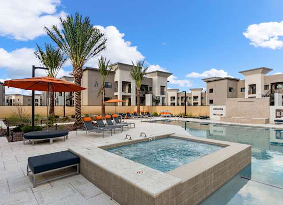 A pool area with a hot tub and lounge chairs.