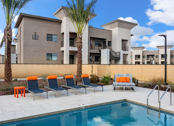 A pool area with chairs and a building in the background.