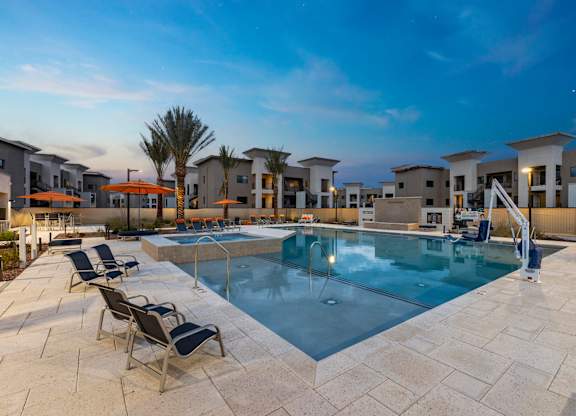A swimming pool surrounded by lounge chairs and palm trees.