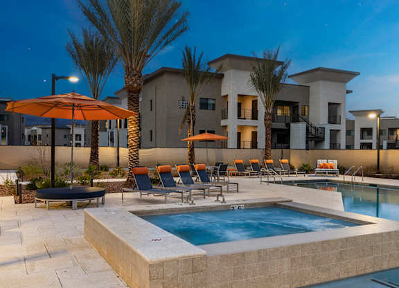 A pool surrounded by chairs and umbrellas in front of a building.
