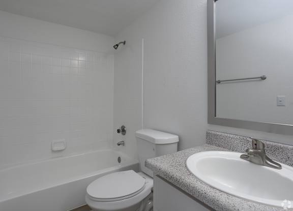 A white bathroom with a toilet, sink, and bathtub.
