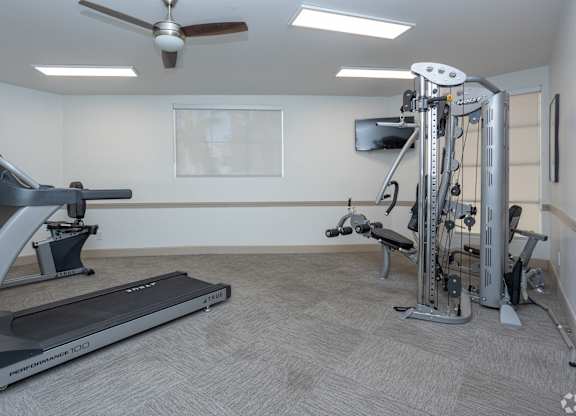 A home gym with a treadmill, a stationary bike, and a multi-gym machine.