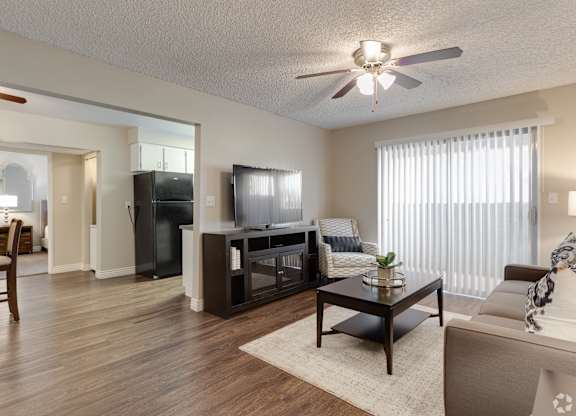 A living room with a wooden floor and a ceiling fan.