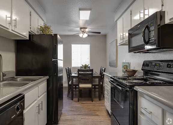 A kitchen with black appliances and white cabinets.