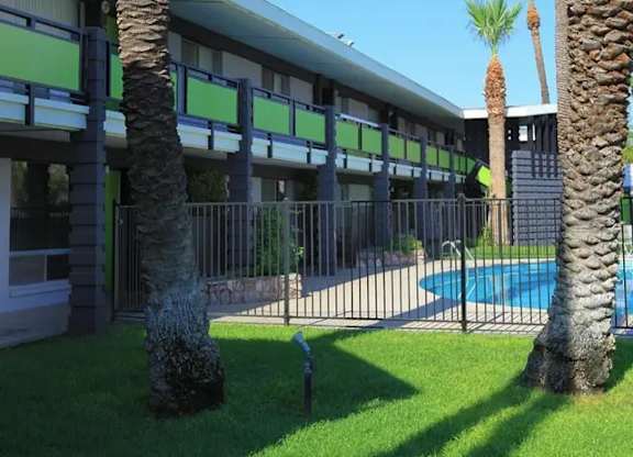 A building with a pool and palm trees in front.