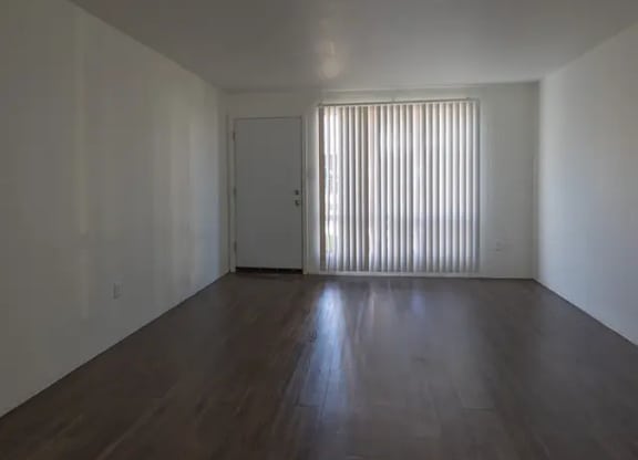 A room with wooden floors and a door with blinds on the window.
