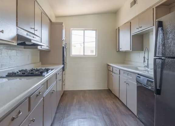 A kitchen with a black stove top oven and a black refrigerator.