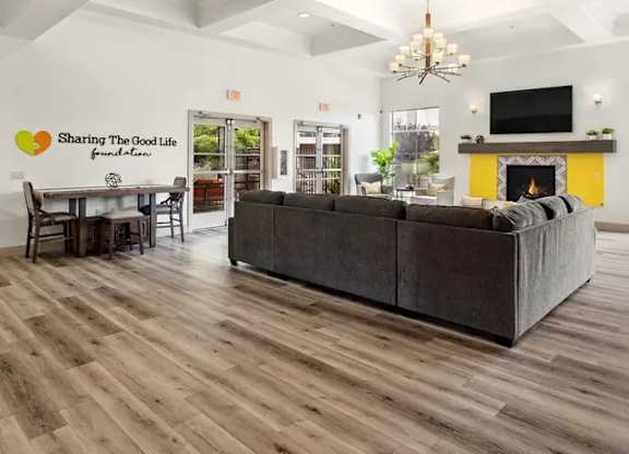 A spacious living room with a grey sofa and a wooden floor.