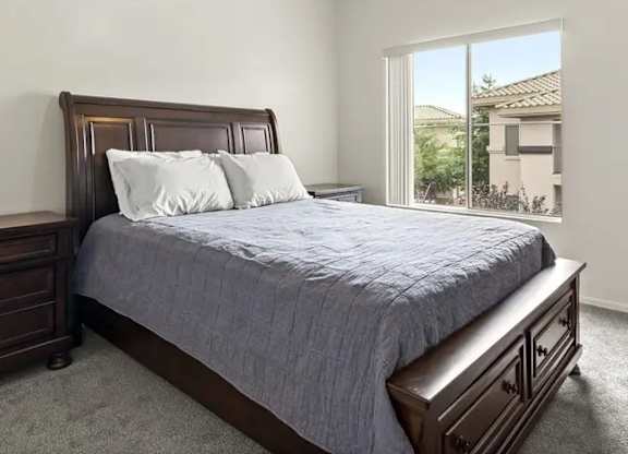 A bedroom with a bed, nightstand, and window.