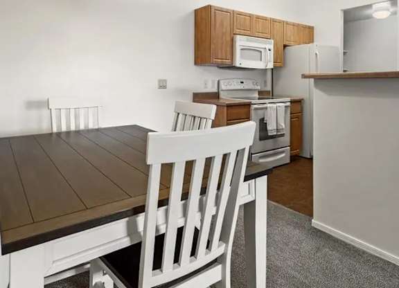 A kitchen with a table and chairs.
