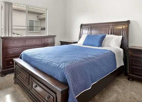 A bedroom with a bed, dresser, and mirror.