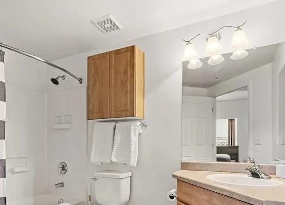 A white toilet in a bathroom with brown flooring and a wooden cabinet.