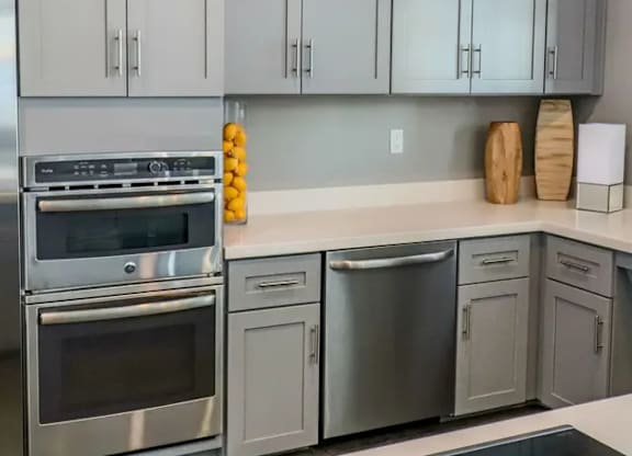 A kitchen with grey cabinets and stainless steel appliances.