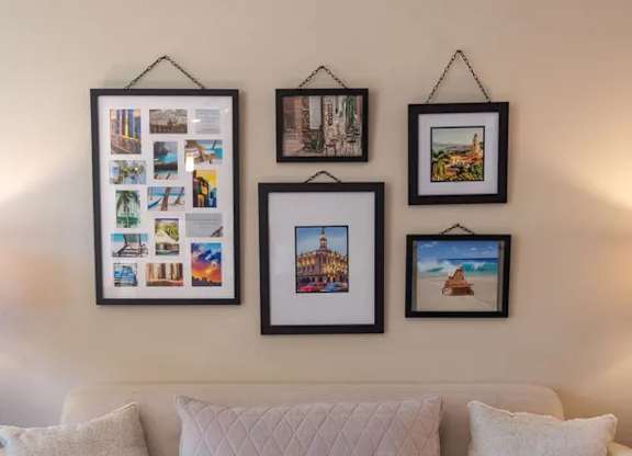 A white couch with a wall hanging picture frame above it.