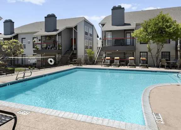 A swimming pool in front of a building with a black fence around it.