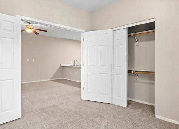 A room with a white door and a ceiling fan.