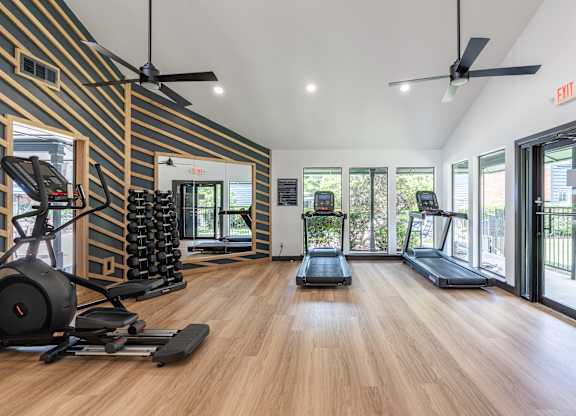 A gym with treadmills, elliptical machines, and weights.
